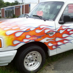 A white truck with flames painted on it.