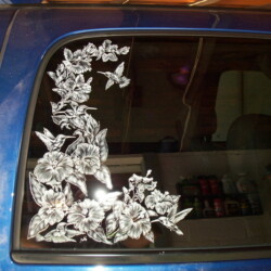 A blue car with a flower window decal.