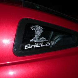 The rear window of a red car with the word shelby on it.