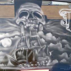 A black and white painting of a pirate ship on the back of a car.