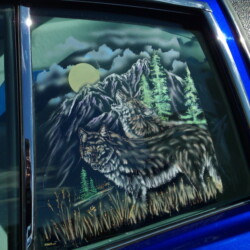A blue car with a wolf in the window.
