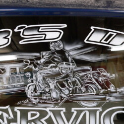 A motorcycle with a man on it on the side of a car.