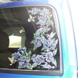 A blue car with flowers on the back window.