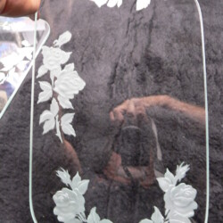 A hand holding a glass with a flower design.