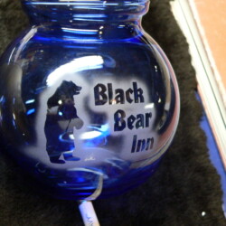 A blue glass vase with a black bear on it.