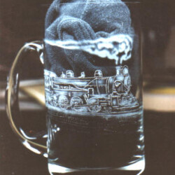 A glass mug with a train on it.