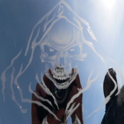An image of a skeleton in the reflection of a car.