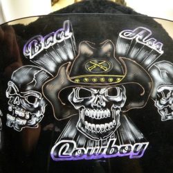 A helmet with skulls and a cowboy hat on it.