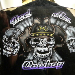 A helmet with skulls and a cowboy hat on it.