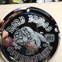 A person is holding a chrome plate with a bulldog on it.