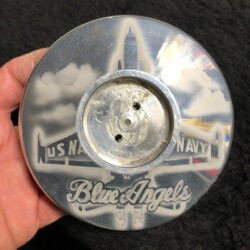 A person is holding a silver plate with a blue angel on it.