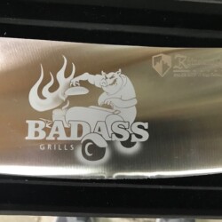 The badass grill logo is on a stainless steel cutting board.